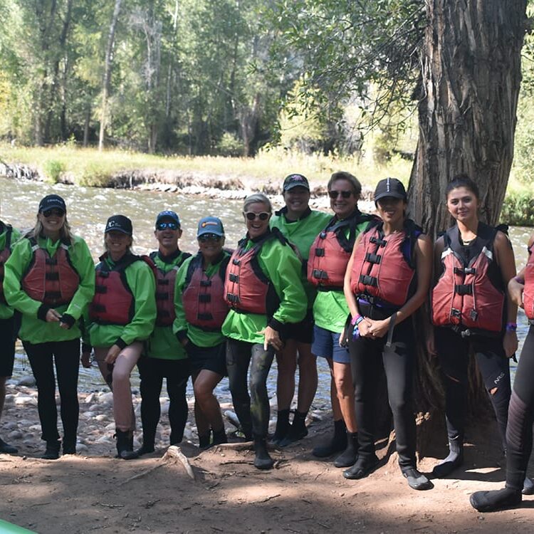 a group posing by the river on their rafting trip in Aspen