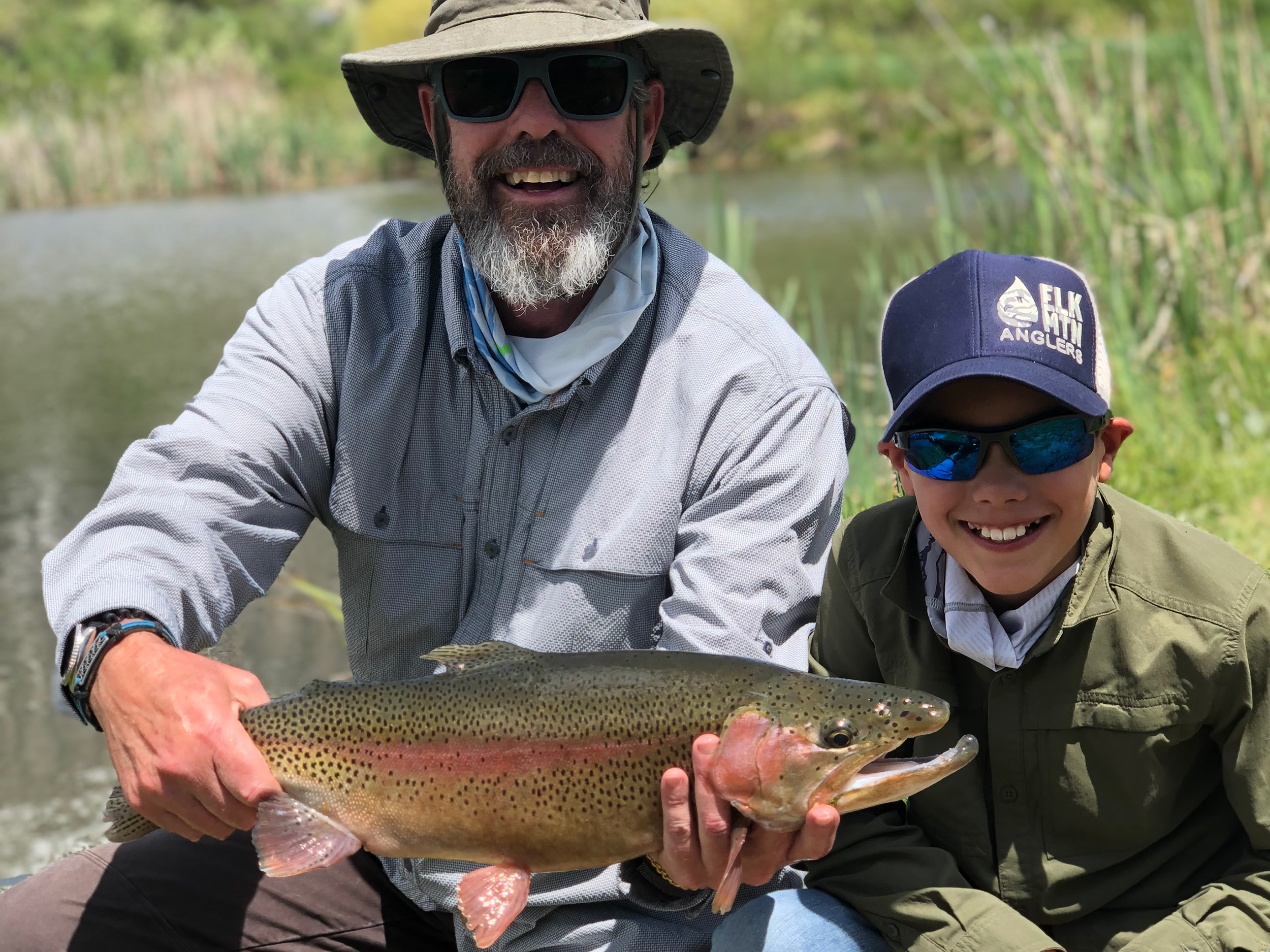 father and son showing the fish they caught fly fishing in Aspen