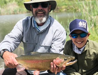father and son showing off their rainbow trout they caught in Aspen