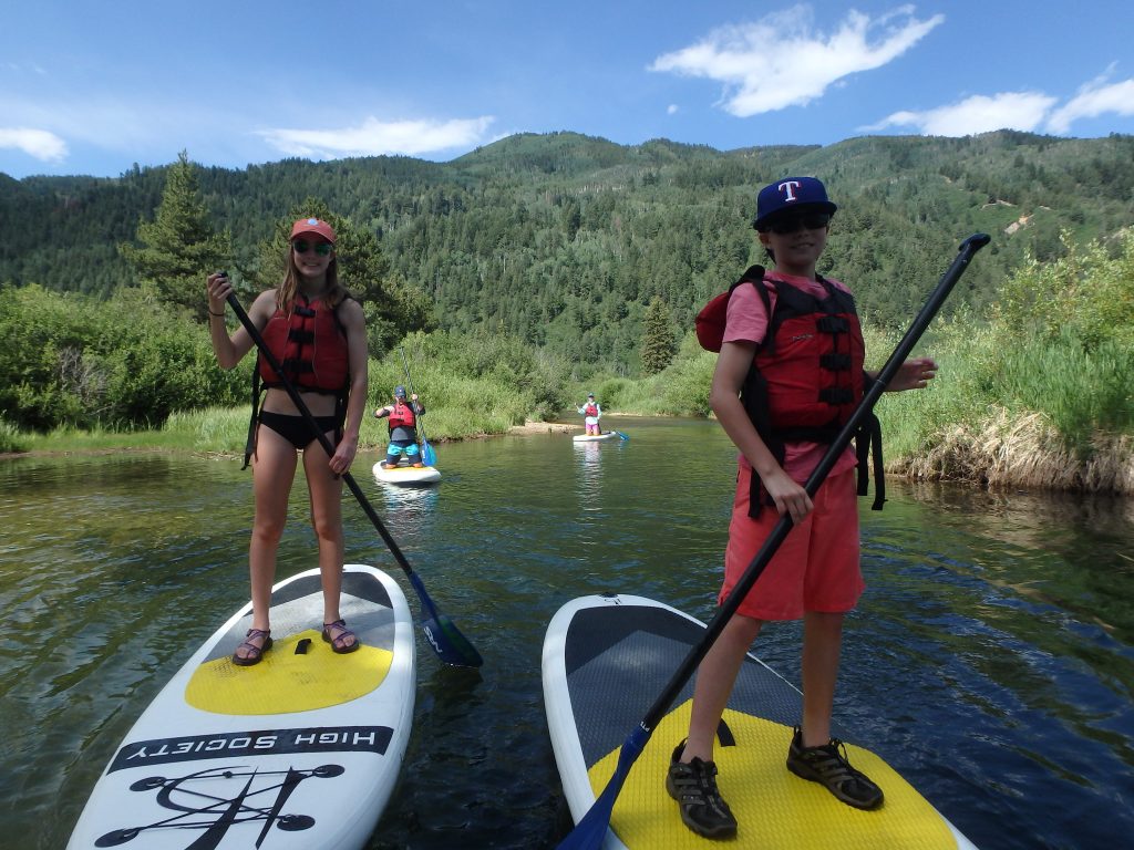 family on stand up paddle boards on the river