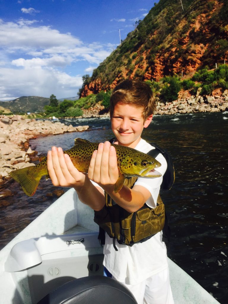 a boy showing the rainbow trout he caught in Aspen