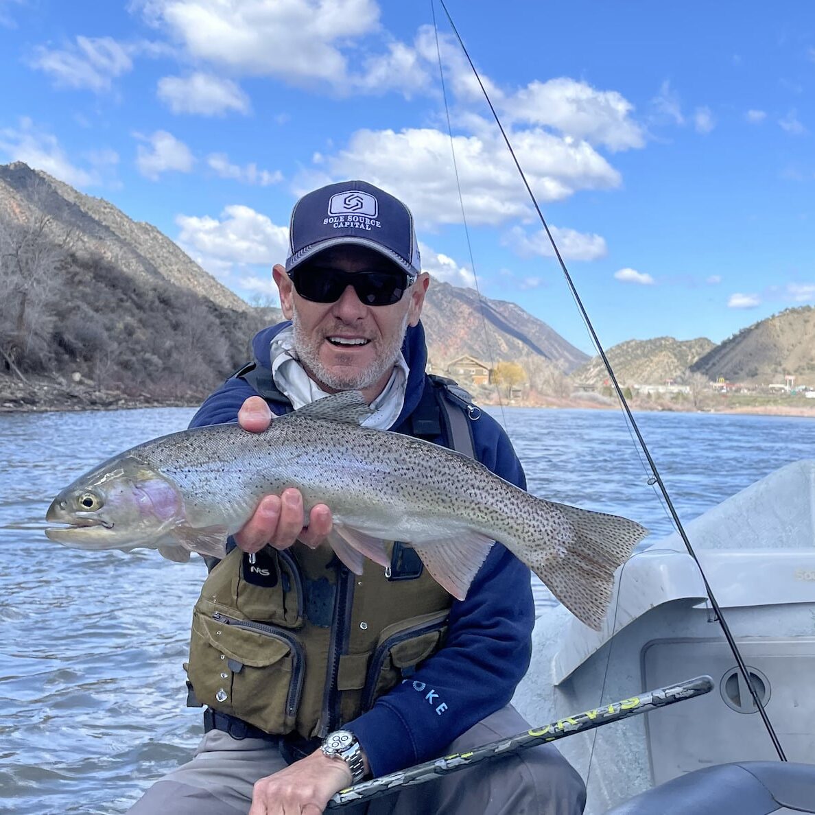 man with showing the rainbow trout he caught fly fishing in Aspen